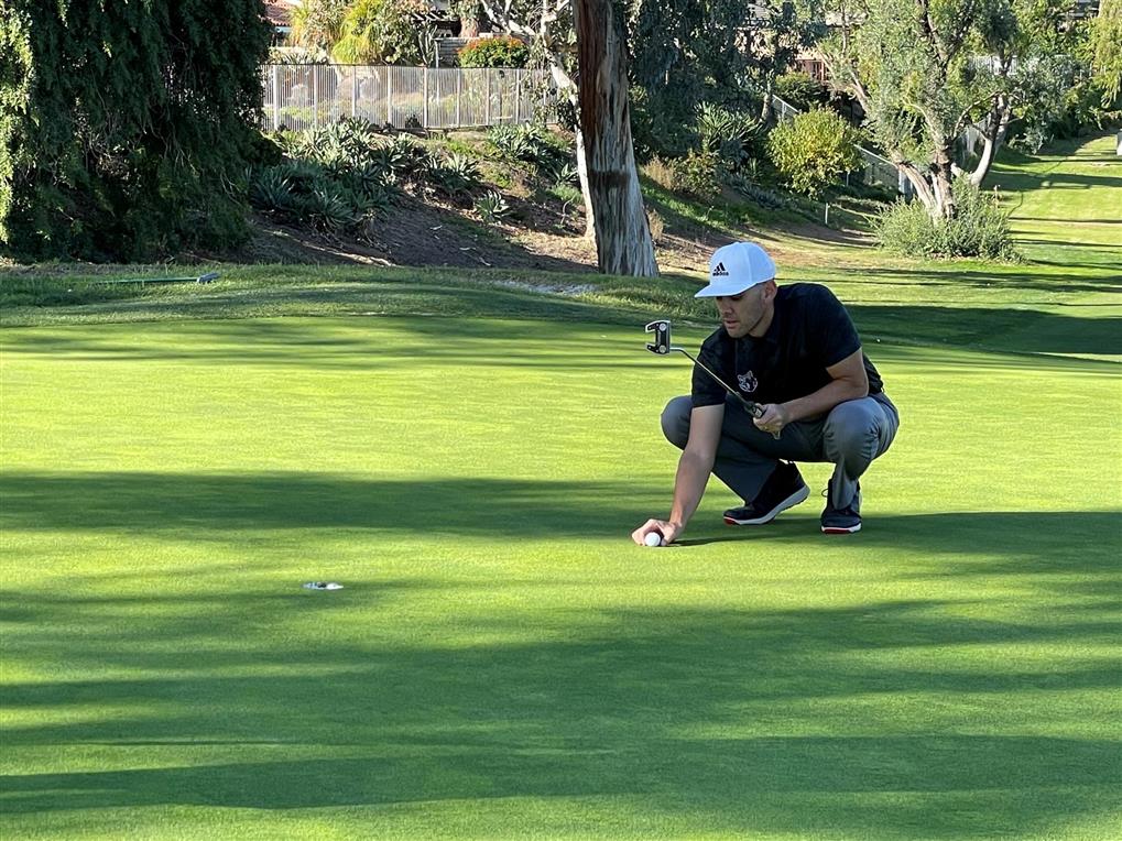 golfer setting up ball on tee