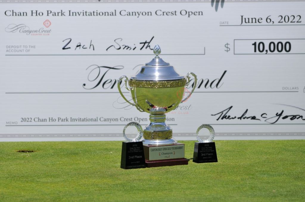 trophy in front of winner's giant check